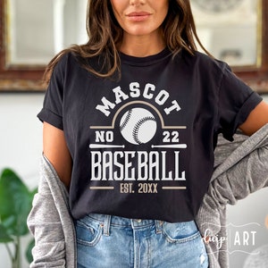 May include: Black t-shirt with a white graphic design that says "MASCOT NO 22 BASEBALL EST. 20XX". The graphic also includes a white baseball with black stitching.