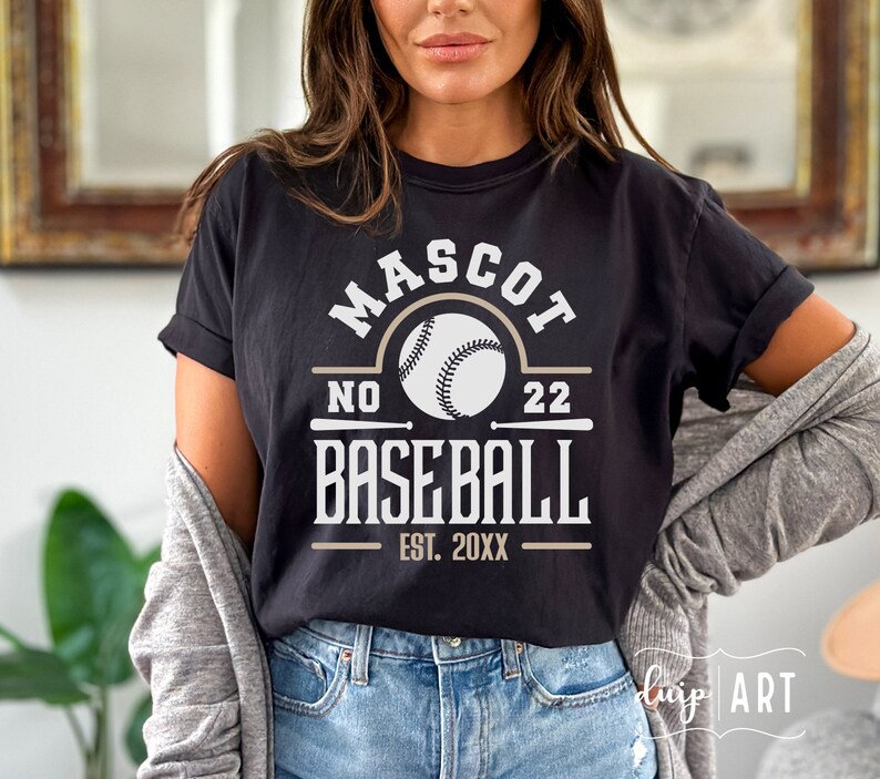 May include: Black t-shirt with a white graphic design that says "MASCOT NO 22 BASEBALL EST. 20XX". The graphic also includes a white baseball with black stitching.