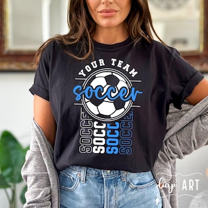 Pu&ograve; includere: Maglietta nera con una grafica di pallone da calcio bianco e il testo "Your Team Soccer" in blu e bianco. Il testo "Soccer" &egrave; ripetuto verticalmente in blu e bianco.
