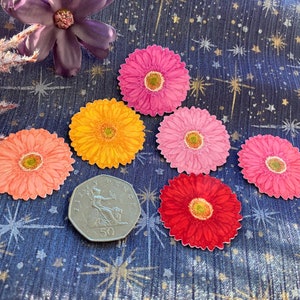 May include: Six colorful paper flower stickers with a star-patterned background. The flowers are pink, orange, red, and a lighter shade of pink. The stickers are arranged in a triangle shape.