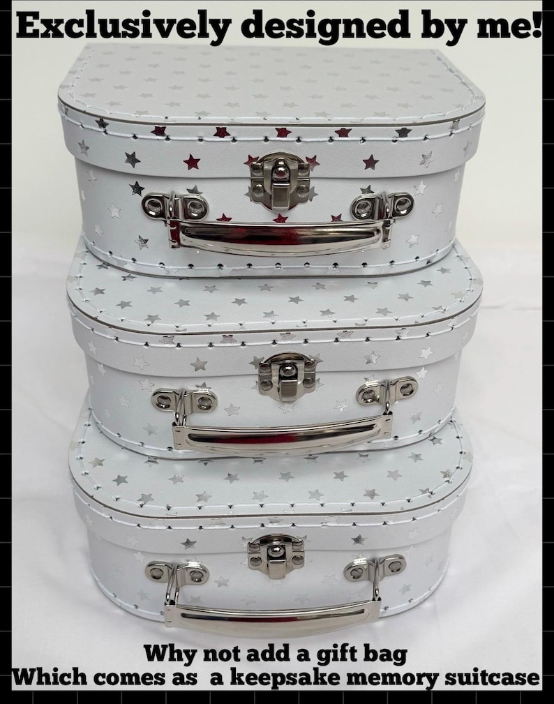 May include: A stack of three white suitcases with silver star patterns, metal latches, and silver handles. The text reads: Exclusively designed by me! Why not add a gift bag Which comes as a keepsake memory suitcase.