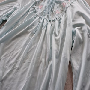May include: A light blue, long-sleeved nightgown with a delicate floral embroidery around the neckline.