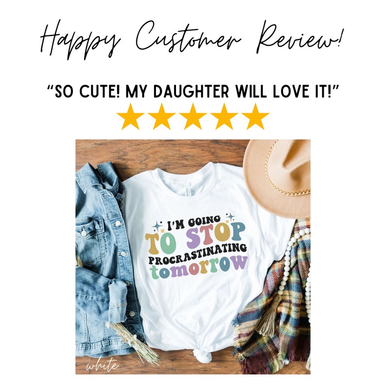 May include: White t-shirt with a colorful graphic that says "I'm going to stop procrastinating tomorrow". The shirt is laid out on a wooden surface with a denim jacket, a straw hat, and a white beaded necklace.