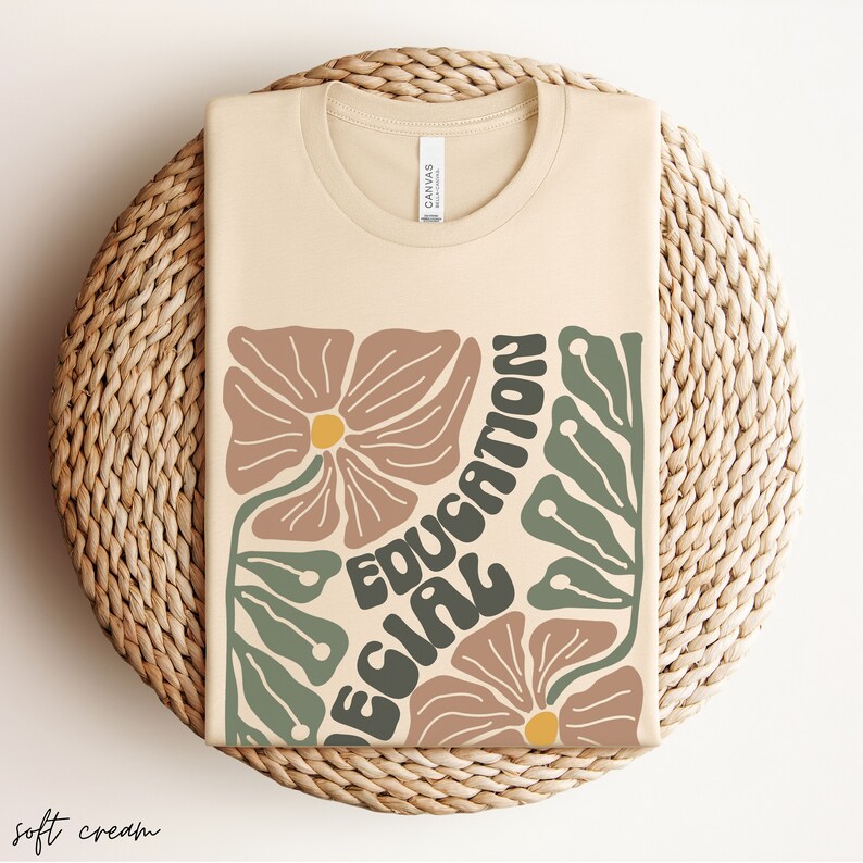 May include: A soft cream coloured t-shirt with a graphic design featuring stylised flowers and the text "Education Girl".