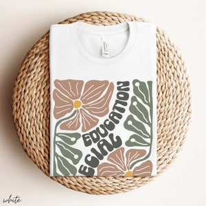 May include: White t-shirt with a graphic design featuring stylised flowers and the text "EQUAL EDUCATION".