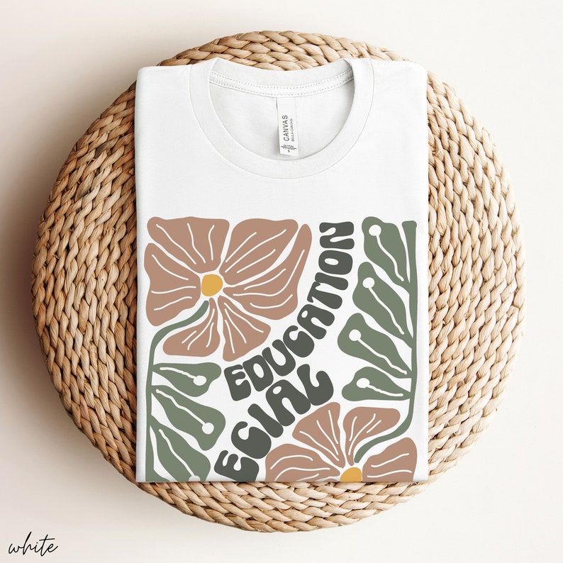 May include: White t-shirt with a graphic design featuring stylised flowers and the text "EQUAL EDUCATION".