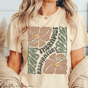 May include: A beige t-shirt with a floral design and the text "Respiratory Therapist" in a retro font.