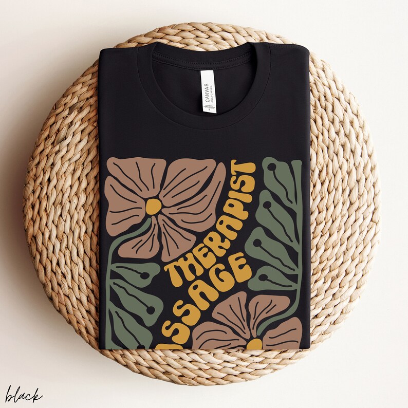 May include: Black t-shirt with a floral design and the text "Massage Therapist" in yellow and orange letters.