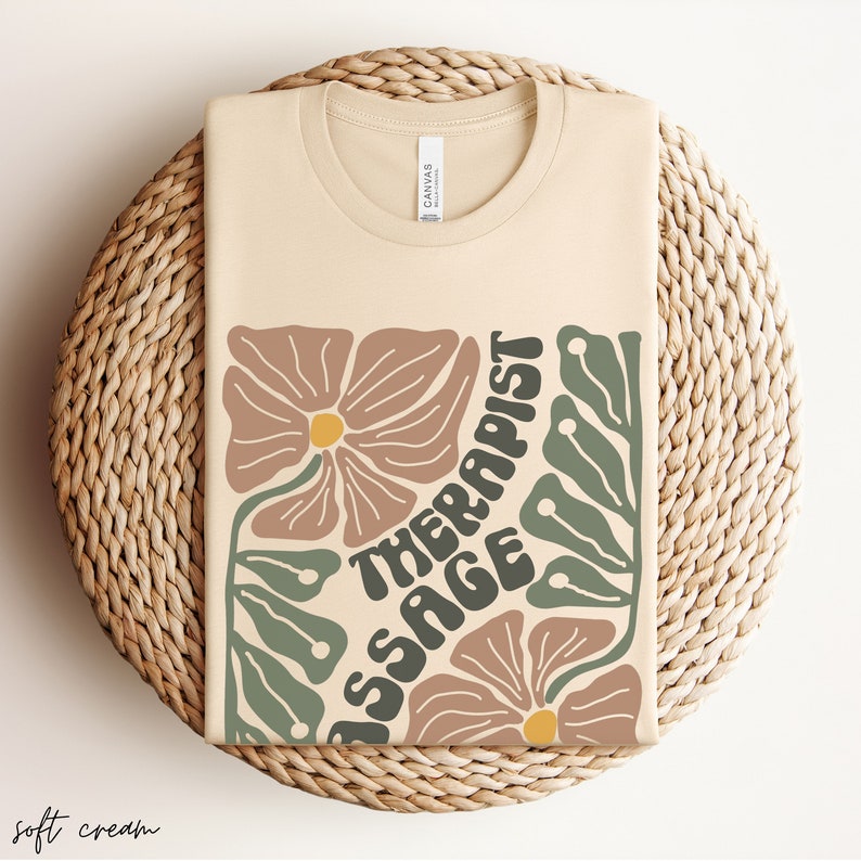 May include: A beige t-shirt with a floral design and the text "Massage Therapist" in a retro font.