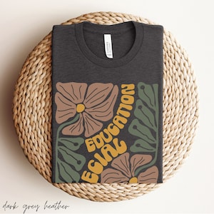 May include: Dark grey heather t-shirt featuring a floral design and the text "Equal Education" in yellow and orange.