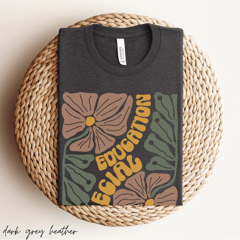 May include: Dark grey heather t-shirt featuring a floral design and the text "Equal Education" in yellow and orange.