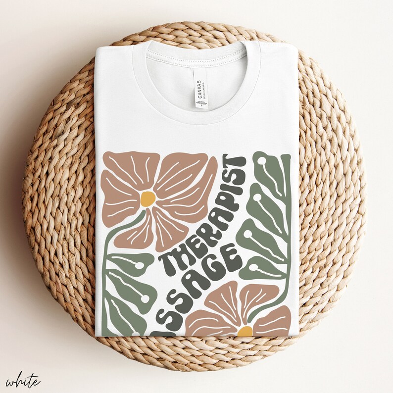 May include: White t-shirt with a floral design and the text "Massage Therapist" in a retro font.