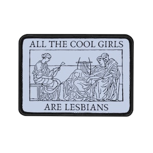 May include: A black and white embroidered patch with a light blue background. The patch features three women playing music and the text "ALL THE COOL GIRLS ARE LESBIANS".