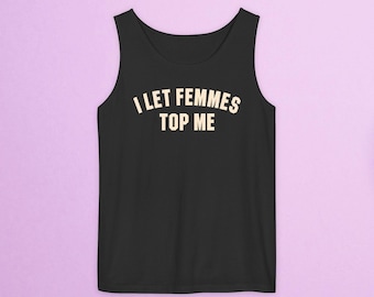 Puede incluir: Camiseta sin mangas negra con el texto "I LET FEMMES TOP ME" en una fuente color crema. La camiseta tiene cuello redondo y es sin mangas. El fondo es de color lila claro sólido.