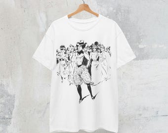 May include: White t-shirt featuring a black and white illustration of a person in historical attire, standing in front of a crowd. The person is wearing a hat, vest, and patterned pants. The design is a graphic print on the front of the shirt.
