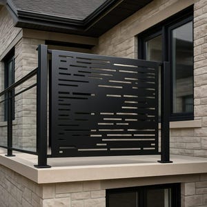May include: Black metal privacy screen with a horizontal cut-out design, installed on a beige stone ledge. The screen is part of a railing system, with a black handrail visible. The background features a brick facade and dark-framed windows.