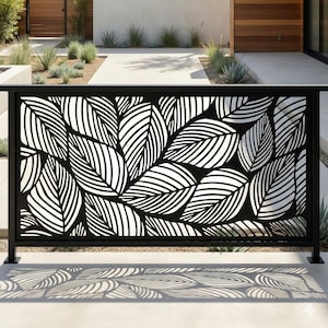 May include: Black metal fence panel with a cut-out leaf design. The leaves are white with detailed veining, set against a black background. The fence is installed outdoors, casting leaf-shaped shadows on the ground.