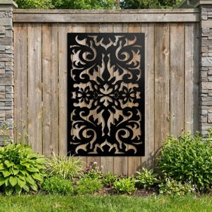 May include: A rectangular black metal privacy screen featuring a symmetrical laser-cut pattern of intricate floral and scrollwork motifs. The panel is mounted vertically, displaying a repeating decorative design with open spaces throughout the surface.