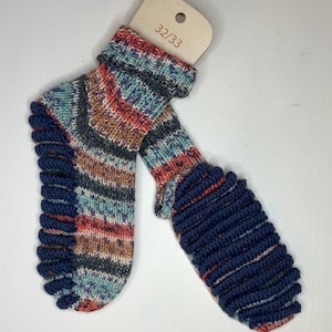 May include: A pair of knitted socks with a colorful pattern of blue, red, brown, and teal. The cuffs and toes are a solid navy blue. A wooden tag with the size 32/33 is attached to the socks.