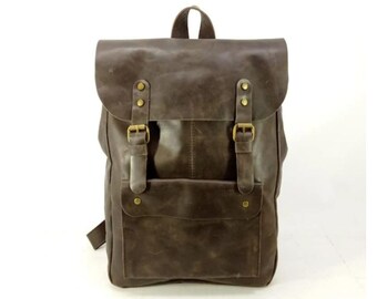 May include: A brown leather backpack with two adjustable buckles and a front pocket. The backpack has a distressed look and is made of high-quality leather.