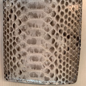 May include: A white snakeskin wallet with a textured surface.