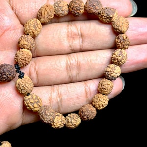 Könnte beinhalten: Ein braunes Holz-Armband mit Perlen und einer schwarzen Schnur, die die Perlen verbindet.