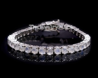 Puede incluir: Un brazalete de tenis de plata con gemas de piedra lunar redondas. El brazalete está sobre un fondo negro.