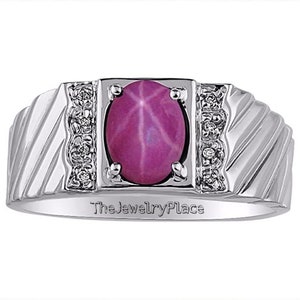 Puede incluir: Un anillo de plata con una piedra preciosa de zafiro estrellado rosa y acentos de diamantes. El anillo tiene una banda texturizada y las palabras "The Jewelry Place" están grabadas en el interior de la banda.