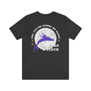May include: A dark heather grey t-shirt with a graphic of a whale jumping in front of a full moon. The text around the moon reads "And you're gonna be happy zero o'clock".