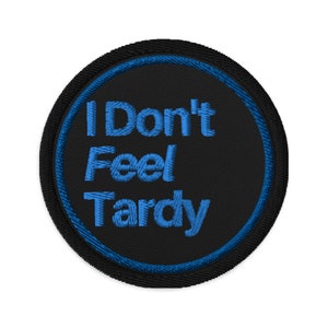 May include: A black and blue embroidered patch with the text "I Don't Feel Tardy" in blue.