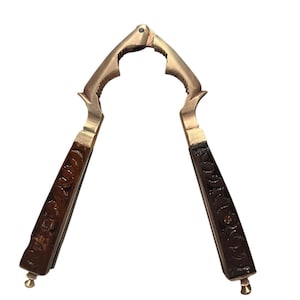 May include: A vintage nutcracker with a brass-colored metal body and dark brown wooden handles. The handles are decorated with a carved floral pattern. The nutcracker is designed with a lever mechanism for cracking nuts.