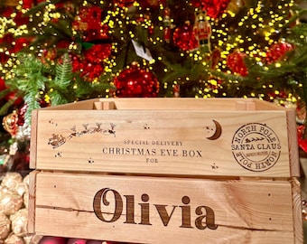 Può includere: Una scatola di legno per la vigilia di Natale con il testo "Special Delivery Christmas Eve Box for Olivia" e un timbro di Babbo Natale del Polo Nord. La scatola è decorata con una luna e stelle.