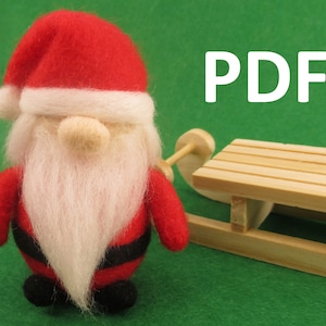 May include: A felt Christmas gnome wearing a red hat with a white trim and a white beard. The gnome is holding a small wooden sled. The image has the word "PDF" in white letters on a green background.
