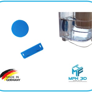 Könnte beinhalten: Drei blaue 3D-gedruckte Teile für einen Wasserfilter. Die Teile sind eine runde Scheibe, ein rechteckiger Block und ein kleinerer rechteckiger Block. Der Text "Made in Germany" ist im Bild sichtbar.