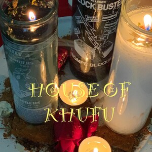 Puede incluir: Tres tarros de velas de vidrio con cera negra, blanca y verde. Las velas est&aacute;n encendidas y las llamas son visibles. Las velas est&aacute;n sobre un plato blanco con una flor roja y una peque&ntilde;a vela de t&eacute;. El texto "HOUSE OF KHUFU" est&aacute; escrito en letras amarillas en el plato.