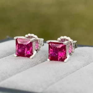 Puede incluir: Un par de pendientes de plata con piedras preciosas rosas cuadradas.