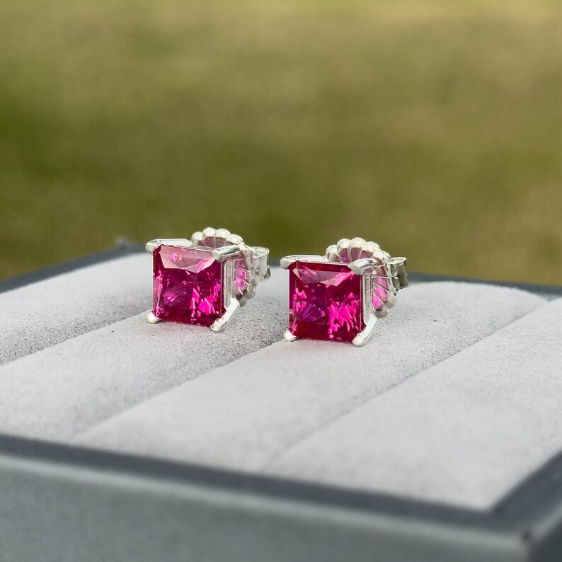 Puede incluir: Un par de pendientes de plata con piedras preciosas rosas cuadradas.