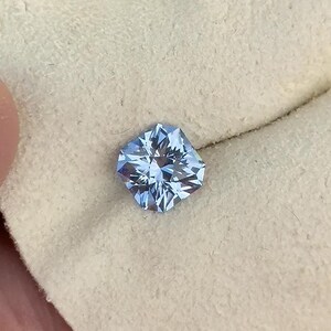 May include: A light blue gemstone with a square shape and a faceted cut.