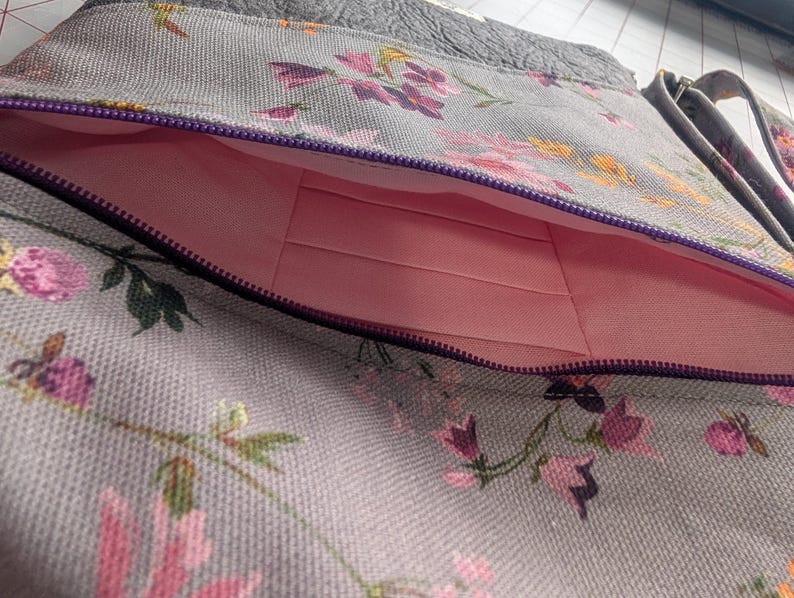 Front pocket with card slots. . Left shoulder, light grey with floral print bag with matching strap and soft, grey faux leather accents.