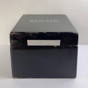 May include: Black wooden box with a silver label that reads "RENATO COLLEZIONI" on the top and "RENATO" on the front.