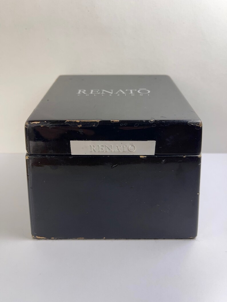 May include: Black wooden box with a silver label that reads "RENATO COLLEZIONI" on the top and "RENATO" on the front.