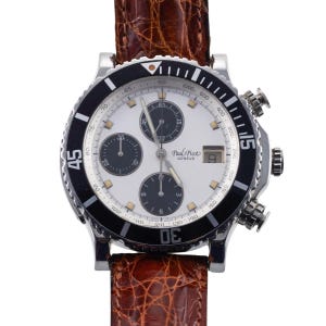 Puede incluir: Un reloj de pulsera de acero inoxidable con esfera blanca, subesferas negras y ventana de fecha. El reloj tiene un bisel negro con marcas blancas y una correa de cuero marrón. La esfera del reloj tiene el texto "Paul Picot Geneve".