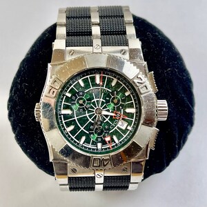 May include: A silver and black wristwatch with a green face and a black rubber strap. The face has a cyclops date window and the text "RENATO CYCLOPS" printed on it.