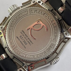 May include: A silver watch with a black rubber strap. The watch face is silver and has the text "Cyclops Collection Hand Made & Assembled 30 ATM Water Resistant" around the edge. The watch face also has the text "Swiss Made Movement ETA 251.272 22 Jewels 62/360 Limited Production" on it.