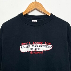 Könnte beinhalten: Schwarzes T-Shirt mit einer roten und weißen Grafik, auf der "don't annoy the anger management class dropout" steht