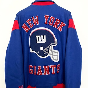 May include: Blue and red varsity jacket with the New York Giants logo and "NEW YORK GIANTS" text on the back. The jacket has a red collar and red trim around the cuffs and bottom.