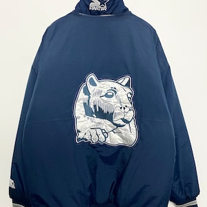 Puede incluir: Chaqueta Starter azul marino con un gran emblema de puma plateado y blanco en la espalda. La chaqueta tiene un cuello alto con el logo de Starter y un dobladillo a rayas. Chaqueta deportiva vintage.