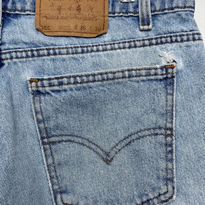 May include: Close-up of light blue denim jeans with a back pocket and a brown leather Levi Strauss & Co. label. The jeans have a waist size of 36 inches and a length of 30 inches.