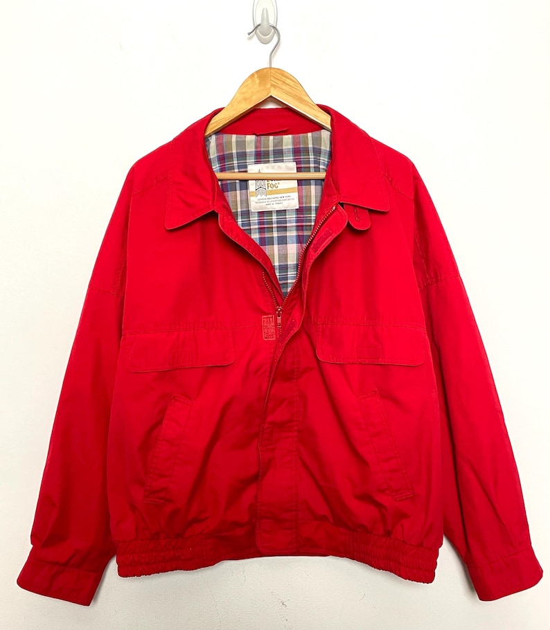 Peut inclure: Une veste rouge avec une fermeture &eacute;clair et une doublure &agrave; carreaux. La veste a deux poches sur le devant et un cordon de serrage au bas.