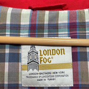 Peut inclure: Une &eacute;tiquette blanche avec des lettres dor&eacute;es qui lisent "London Fog" avec une image stylis&eacute;e du Big Ben. L'&eacute;tiquette comprend &eacute;galement le texte "London, Baltimore, New York, Trademarks of Londontown Corporation, Made in Turkey."